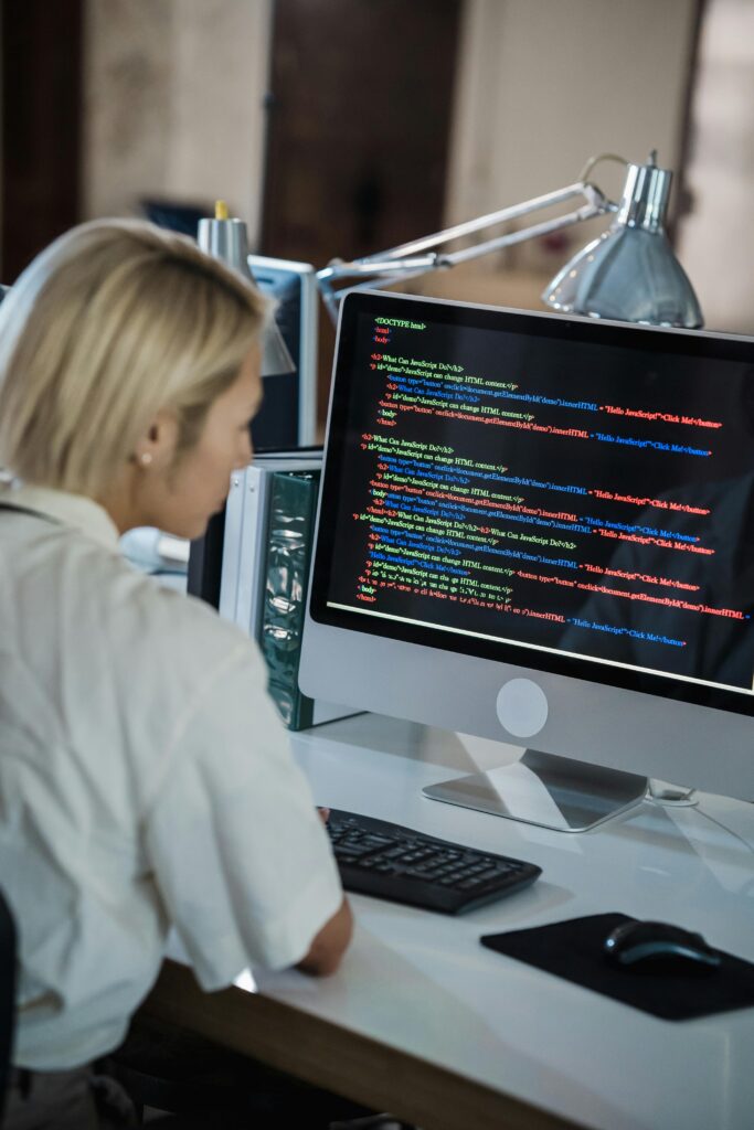 Home Woman with blonde hair coding on computer in a modern office setting.